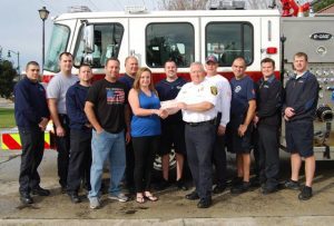 Jesse and Theresa Faircloth present Goose Creek Fire Chief Steve Chapman with a check for $8,000 on the morning of Dec. 3, as GCFD firefighters look on.